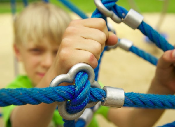 child holding on to rope climbing feature